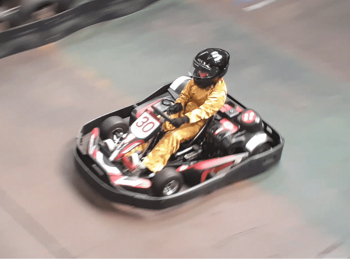 Disabled Baddie Betty driving a Go-Kart with one hand, at indoor track.