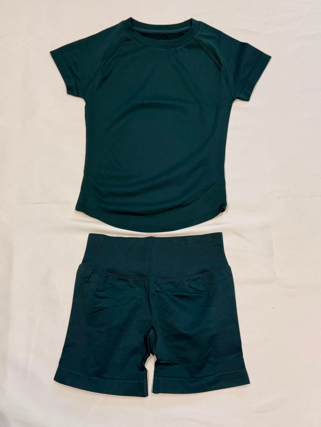 Pearl, Pine Green, Ladies Gym set. Short-sleeve top and matching high-waisted shorts with scrunch bum, laid flat.
